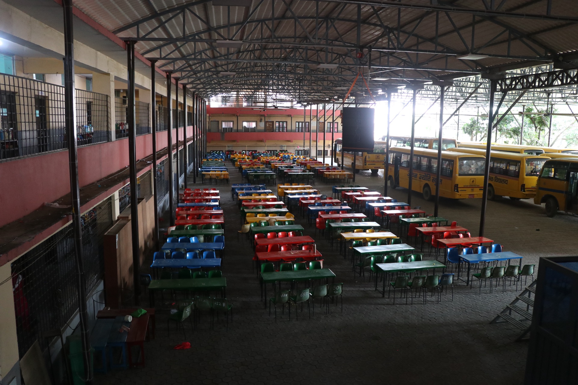 Large covered auditorium with seating arrangements and school buses