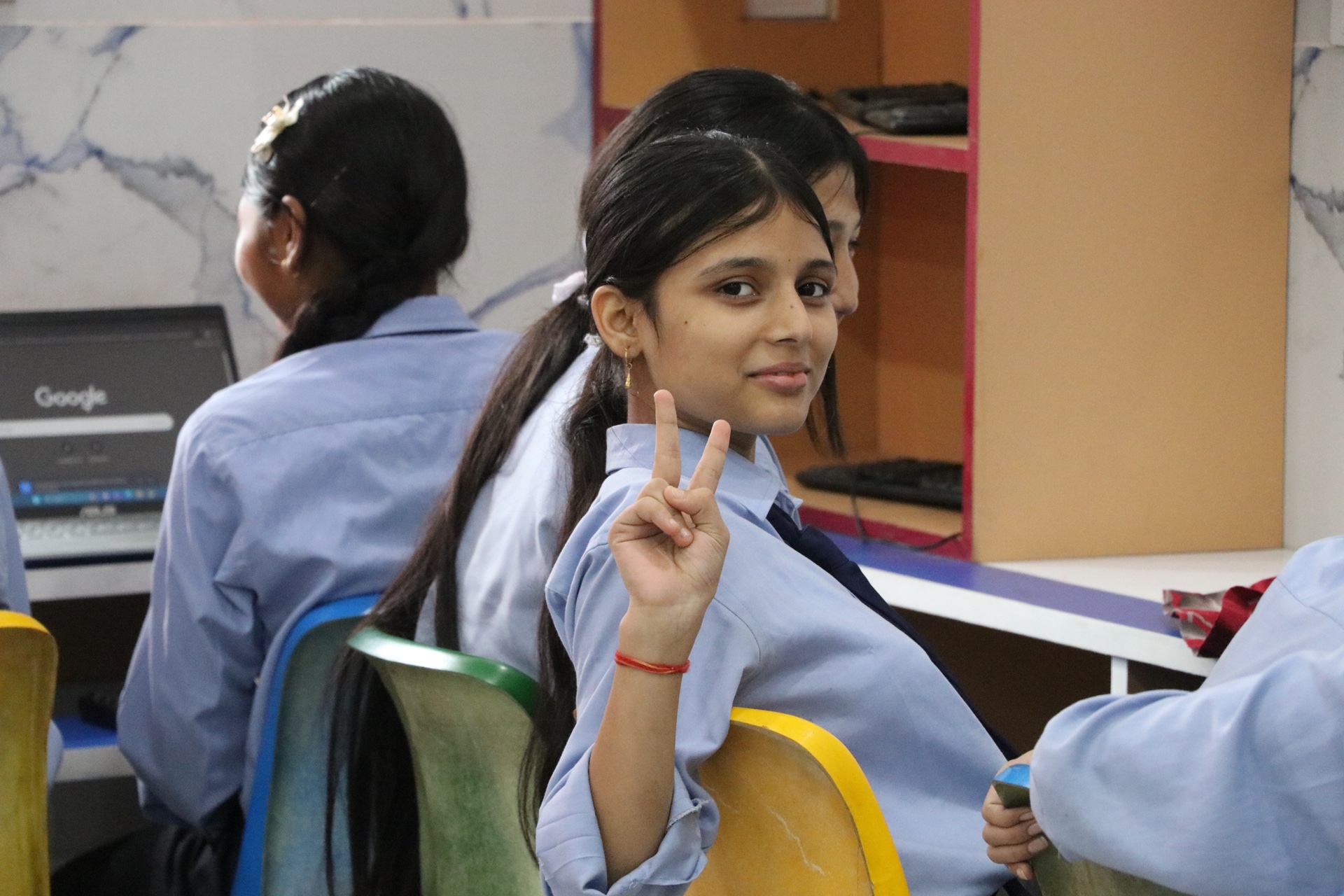 Smiling student giving peace sign during computer session