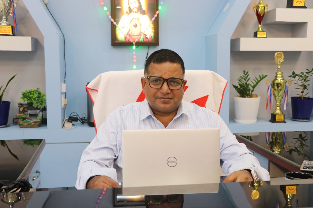 Principal Fr. Jomon James at executive leadership desk